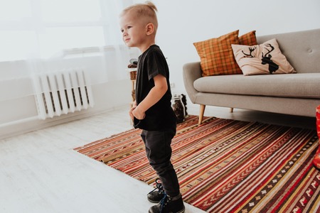 Cool trendy hipster boy 2 years old wears yellow jacket posing at the decorated photozone of autumn decor with beautiful bright autumn leaves. Cosy atmosphereの写真素材