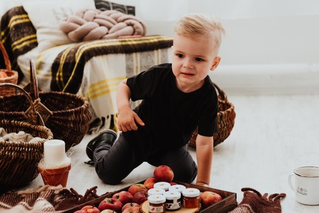 Cool trendy hipster boy 2 years old wears yellow jacket posing at the decorated photozone of autumn decor with beautiful bright autumn leaves. Cosy atmosphereの写真素材