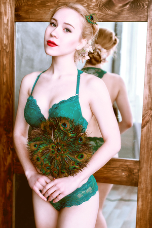 Beautiful girl with bright colored makeup and peacock feather on a black background. Beauty.の写真素材