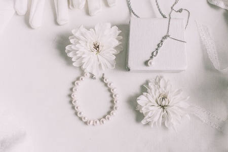 White bridal accessories for wedding background with pearls, white satin ribbons and lace, gloves, bracelet,flat lay for fashion blog, top viewの写真素材