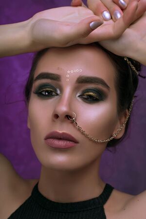 Girl with cool fashionable make-up posing in studio,matte lips and nails,cate eyes,smokey gold eyes,...