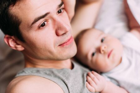 Portrait of loving father with baby boy 4-6 months his son at home on white