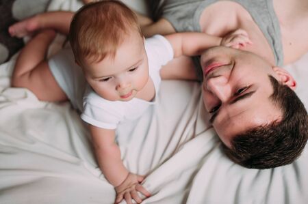 Portrait of loving father with baby boy 4-6 months his son at home on white