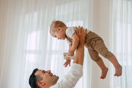 Portrait of handsome Father and son 1 year old having fun happy and smiling hugging in studio at the day time. Concept of friendly family.の写真素材