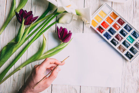 Palette of watercolor paints, brushes and paper for a water color on wooden background, close up. Flat lay, spring background with copy space.の写真素材