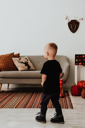 Cool trendy hipster boy 2 years old wears yellow jacket posing at the decorated photozone of autumn decor with beautiful bright autumn leaves. Cosy atmosphereの写真素材