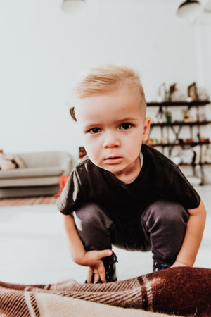Cool trendy hipster boy 2 years old wears yellow jacket posing at the decorated photozone of autumn decor with beautiful bright autumn leaves. Cosy atmosphereの写真素材