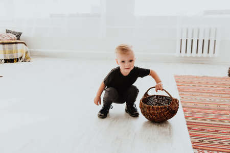 Cool trendy hipster boy 2 years old wears yellow jacket posing at the decorated photozone of autumn decor with beautiful bright autumn leaves. Cosy atmosphereの写真素材