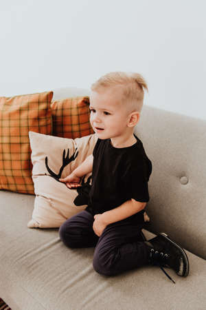 Cool trendy hipster boy 2 years old wears yellow jacket posing at the decorated photozone of autumn...