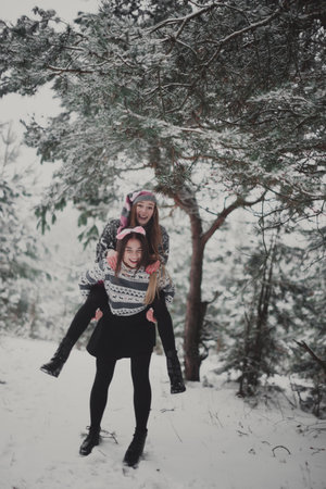 Two young teenage hipster girl friends together.Close up fashion portrait of two sisters hugs and having fun winter time,wearing sweater,best friends couple outdoors, snowy weatherの写真素材