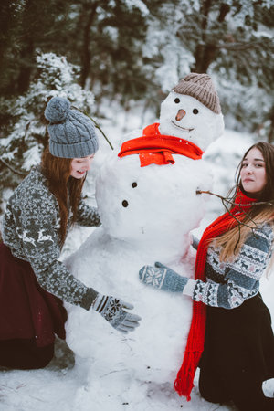 Two young teenage hipster girl friends together.Close up fashion portrait of two sisters hugs and having fun winter time,wearing sweater,best friends couple outdoors, snowy weatherの写真素材