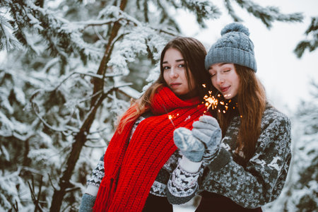 Two young teenage hipster girl friends together.Close up fashion portrait of two sisters hugs and having fun winter time,wearing sweater,best friends couple outdoors, snowy weatherの写真素材