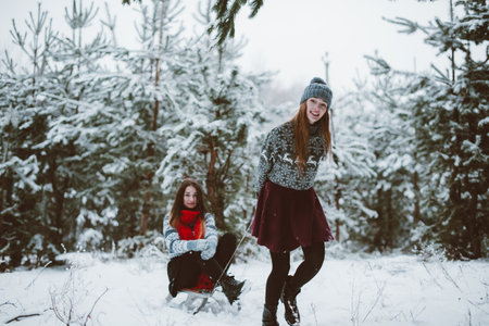 Two young teenage hipster girl friends together.Close up fashion portrait of two sisters hugs and having fun winter time,wearing sweater,best friends couple outdoors, snowy weatherの写真素材