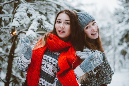 Two young teenage hipster girl friends together.Close up fashion portrait of two sisters hugs and having fun winter time,wearing sweater,best friends couple outdoors, snowy weatherの写真素材
