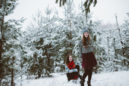 Two young teenage hipster girl friends together.Close up fashion portrait of two sisters hugs and having fun winter time,wearing sweater,best friends couple outdoors, snowy weatherの写真素材