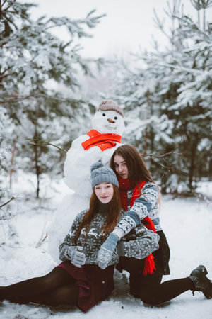 Two young teenage hipster girl friends together.Close up fashion portrait of two sisters hugs and having fun winter time,wearing sweater,best friends couple outdoors, snowy weatherの写真素材