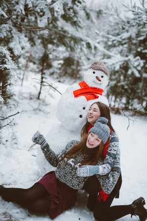 Two young teenage hipster girl friends together.Close up fashion portrait of two sisters hugs and having fun winter time,wearing sweater,best friends couple outdoors, snowy weatherの写真素材