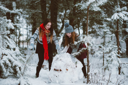 Two young teenage hipster girl friends together.Close up fashion portrait of two sisters hugs and having fun winter time,wearing sweater,best friends couple outdoors, snowy weatherの写真素材