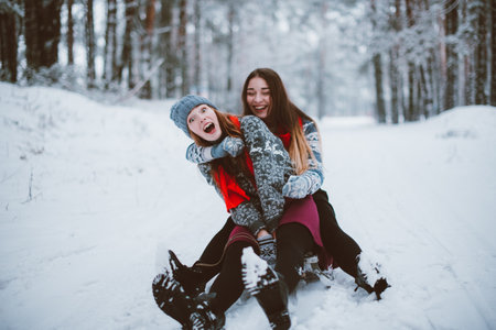Two young teenage hipster girl friends together.Close up fashion portrait of two sisters hugs and having fun winter time,wearing sweater,best friends couple outdoors, snowy weatherの写真素材