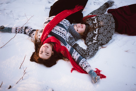 Two young teenage hipster girl friends together.Close up fashion portrait of two sisters hugs and having fun winter time,wearing sweater,best friends couple outdoors, snowy weatherの写真素材