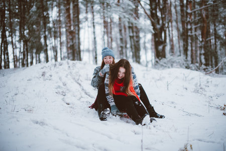 Two young teenage hipster girl friends together.Close up fashion portrait of two sisters hugs and having fun winter time,wearing sweater,best friends couple outdoors, snowy weatherの写真素材