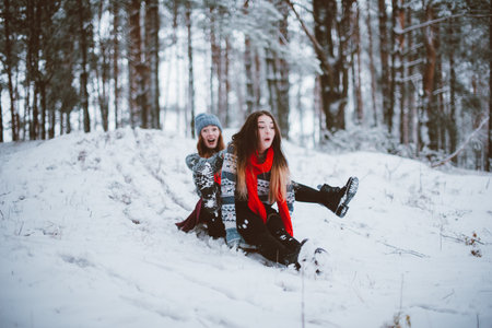 Two young teenage hipster girl friends together.Close up fashion portrait of two sisters hugs and having fun winter time,wearing sweater,best friends couple outdoors, snowy weatherの写真素材