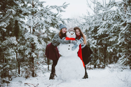 Two young teenage hipster girl friends together.Close up fashion portrait of two sisters hugs and having fun winter time,wearing sweater,best friends couple outdoors, snowy weatherの写真素材