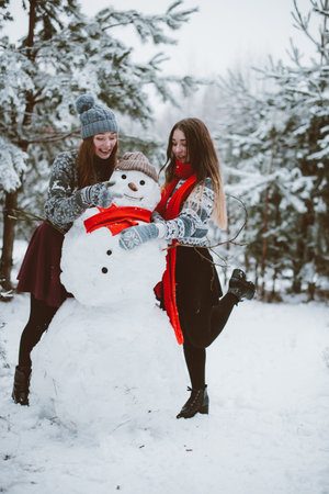 Two young teenage hipster girl friends together.Close up fashion portrait of two sisters hugs and having fun winter time,wearing sweater,best friends couple outdoors, snowy weatherの写真素材