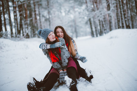 Two young teenage hipster girl friends together.Close up fashion portrait of two sisters hugs and having fun winter time,wearing sweater,best friends couple outdoors, snowy weatherの写真素材