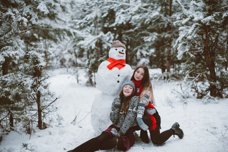Two young teenage hipster girl friends together.Close up fashion portrait of two sisters hugs and having fun winter time,wearing sweater,best friends couple outdoors, snowy weatherの写真素材
