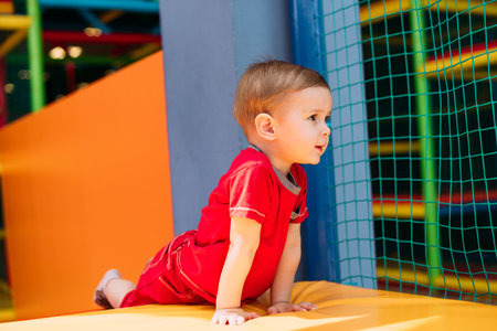 Happy laughing boy 1-2 years old having fun in ball pit on birthday party in kids amusement park and indoor play center. Child playing with colorful balls in playground ball pool. Activity toys for little kid.の写真素材