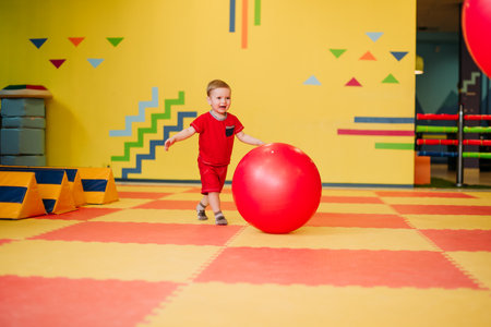 Happy laughing boy 1-2 years old having fun in ball pit on birthday party in kids amusement park and indoor play center. Child playing with colorful balls in playground ball pool. Activity toys for little kid.の写真素材