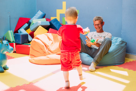 Happy laughing boy 1-2 years old having fun in ball pit on birthday party in kids amusement park and indoor play center. Child playing with colorful balls in playground ball pool. Activity toys for little kid.の写真素材