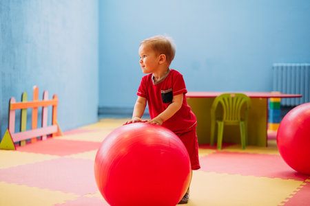 Happy laughing boy 1-2 years old having fun in ball pit on birthday party in kids amusement park and indoor play center. Child playing with colorful balls in playground ball pool. Activity toys for little kid.の写真素材