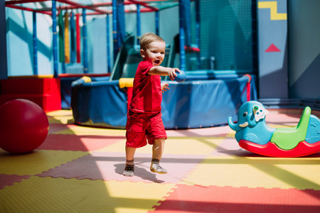 Happy laughing boy 1-2 years old having fun in ball pit on birthday party in kids amusement park and indoor play center. Child playing with colorful balls in playground ball pool. Activity toys for little kid.の写真素材