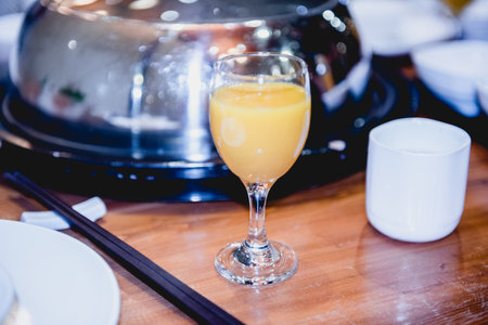 glass of orange juice with chopsticks on a table