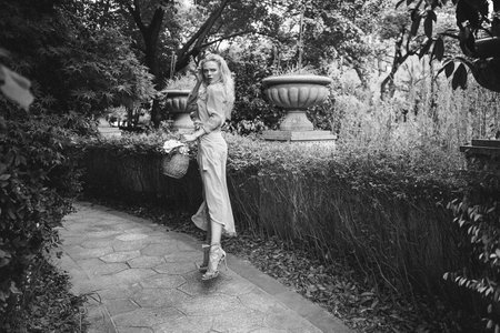 Sensual young blonde beautiful cute and elegant woman wearing pink sitting on the rock and looking into the camera over tropical green jungle palm background in China.の写真素材