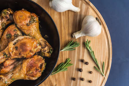 Baked chicken legs with herbs and spice on wooden standの写真素材