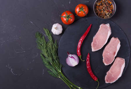 Raw pork meat steak with spice on dark backgroundの写真素材
