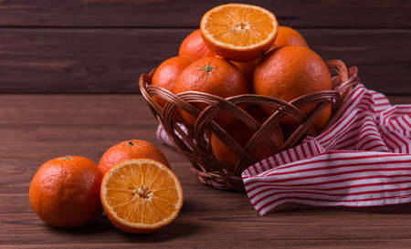 Delicious and beautiful fresh tangerines in wicker basket on wooden backgroundの写真素材