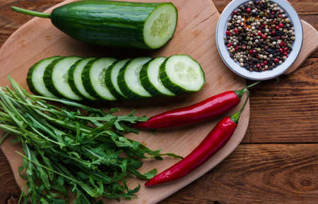 Cucumber on wooden board with spice pepper and arugulaの写真素材