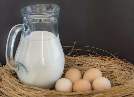 Pitcher with milk and eggs in the wicker basketの写真素材