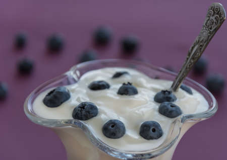 Yougurt in glass with blueberry and spoon