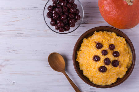 Homemade pumpkin porridge with preserved cherries and whole pumpkinの写真素材