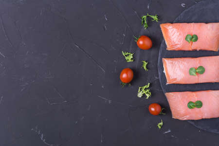 Raw salmon steak with herbs and spice on dark backgroundの写真素材