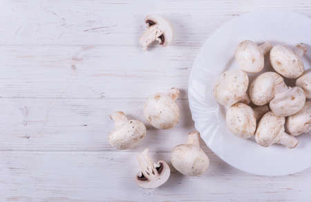 Fresh brown champignon mushrooms in white plate on white backgroundの写真素材