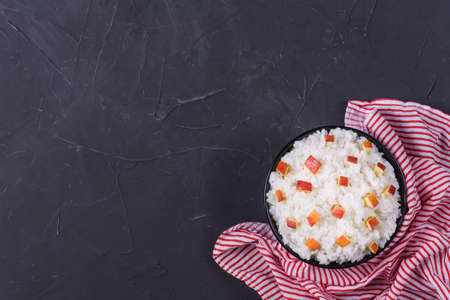 Boiled rice with apples,walnuts and cinnamon on dark background