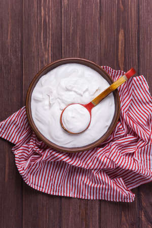 Yogurt in clay plate with spoon on wooden backgroundの写真素材