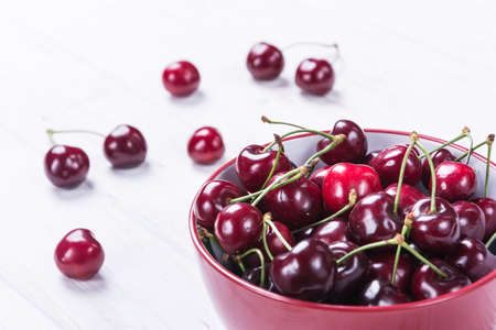 Fresh ripe delicious cherry in red bowl on white backgroundの写真素材