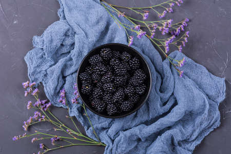 Ripe blackberry fruit with pink flowers on dark background